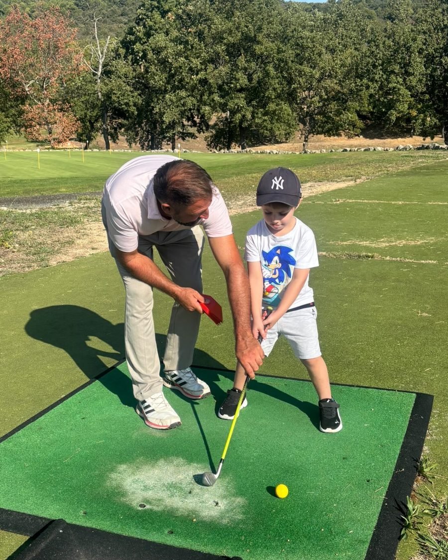 Éric Poujeol guide un enfant du Baby Golf pour son premier swing, sur le practice du Golf du Claux Amic